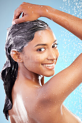 Buy stock photo Shot of a young woman washing her hair in the shower against a blue background