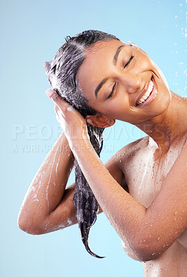 Buy stock photo Shot of a young woman washing her hair in the shower against a blue background