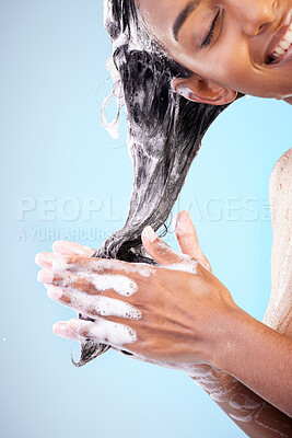 Buy stock photo Shot of a young woman washing her hair in the shower against a blue background