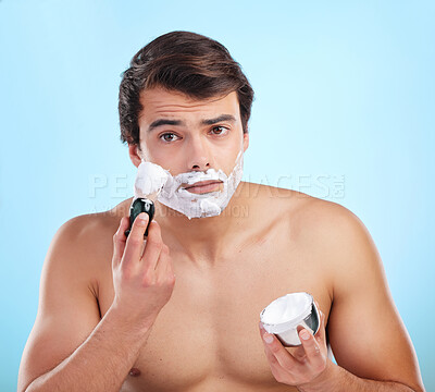 Buy stock photo Beauty, man and shaving cream brush in studio for hair removal, hygiene and grooming portrait on blue background. Face, beard and model apply foam for skincare, cleaning and wellness with container