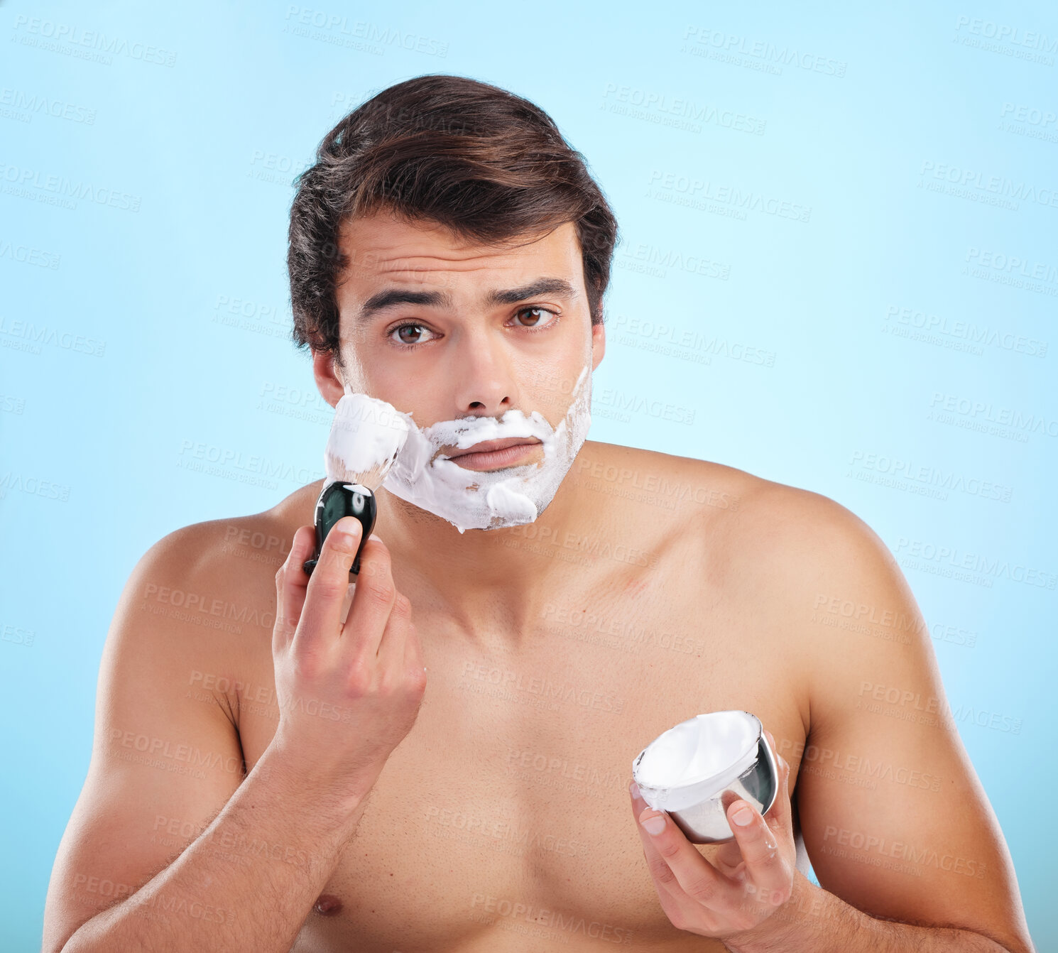 Buy stock photo Beauty, man and shaving cream brush in studio for hair removal, hygiene and grooming portrait on blue background. Face, beard and model apply foam for skincare, cleaning and wellness with container