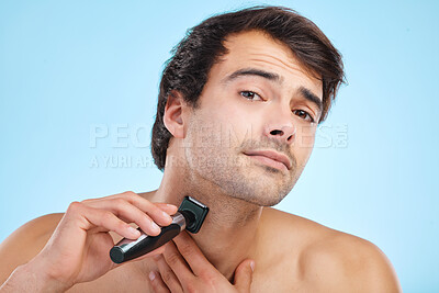 Buy stock photo Man, shaving and face with electric razor on studio backdrop for personal hygiene and skin care. Male person, beauty and portrait and grooming by blue background for beard, hair removal and cosmetics