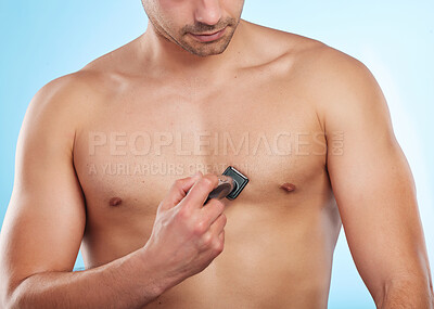 Buy stock photo Shaving chest, person and grooming in studio for hair removal, wellness or skincare on blue background. Man, topless and electric shaver for hygiene with razor, trimming or aesthetic or personal care