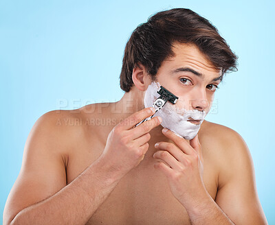 Buy stock photo Portrait, razor and man shaving with foam for hair removal, hygiene or grooming isolated on blue background in studio. Cream, face and model cut beard for skincare, beauty and cleaning for wellness