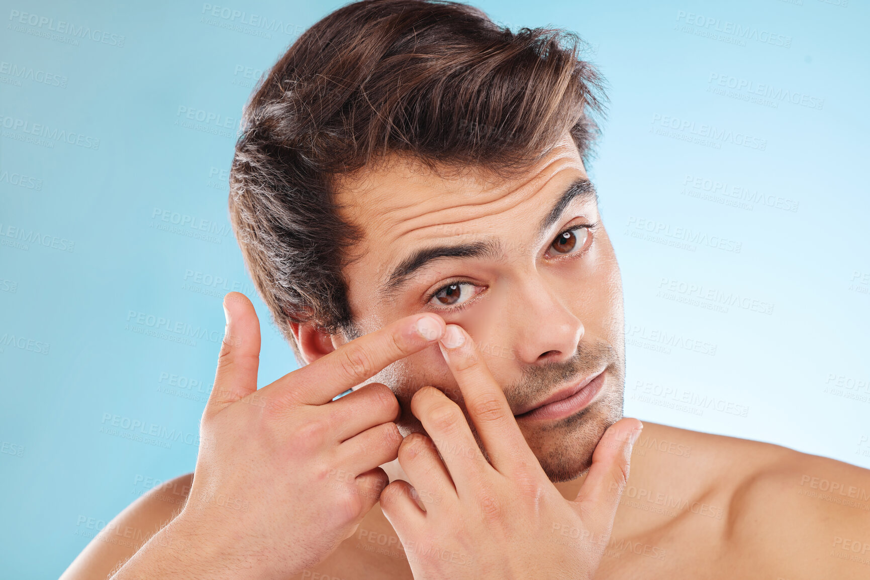 Buy stock photo Grooming, man and squeezing pimple in morning, routine and wellness in skincare, hygiene and blue background. Male person, cosmetic and popping for blemish, confidence and clean in studio backdrop
