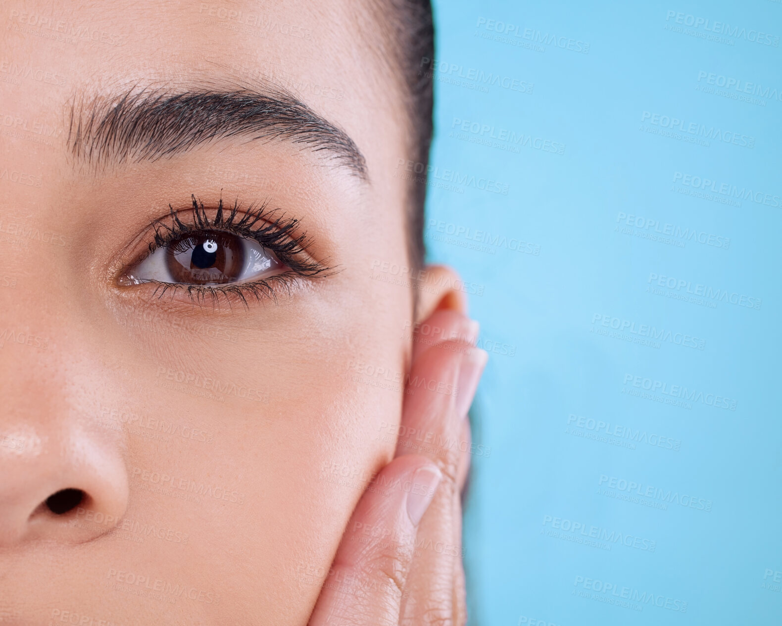 Buy stock photo Studio, eye and half portrait of girl with cosmetics, facial skincare and makeup for lashes. Beauty, dermatology and face of woman with mascara, eyebrow and healthy skin wellness on blue background.