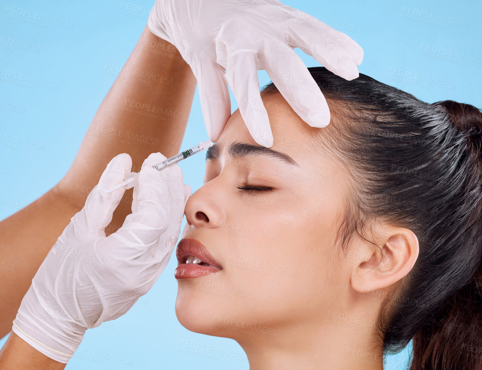 Buy stock photo Studio shot of an attractive young woman having some plastic surgery done against a blue background