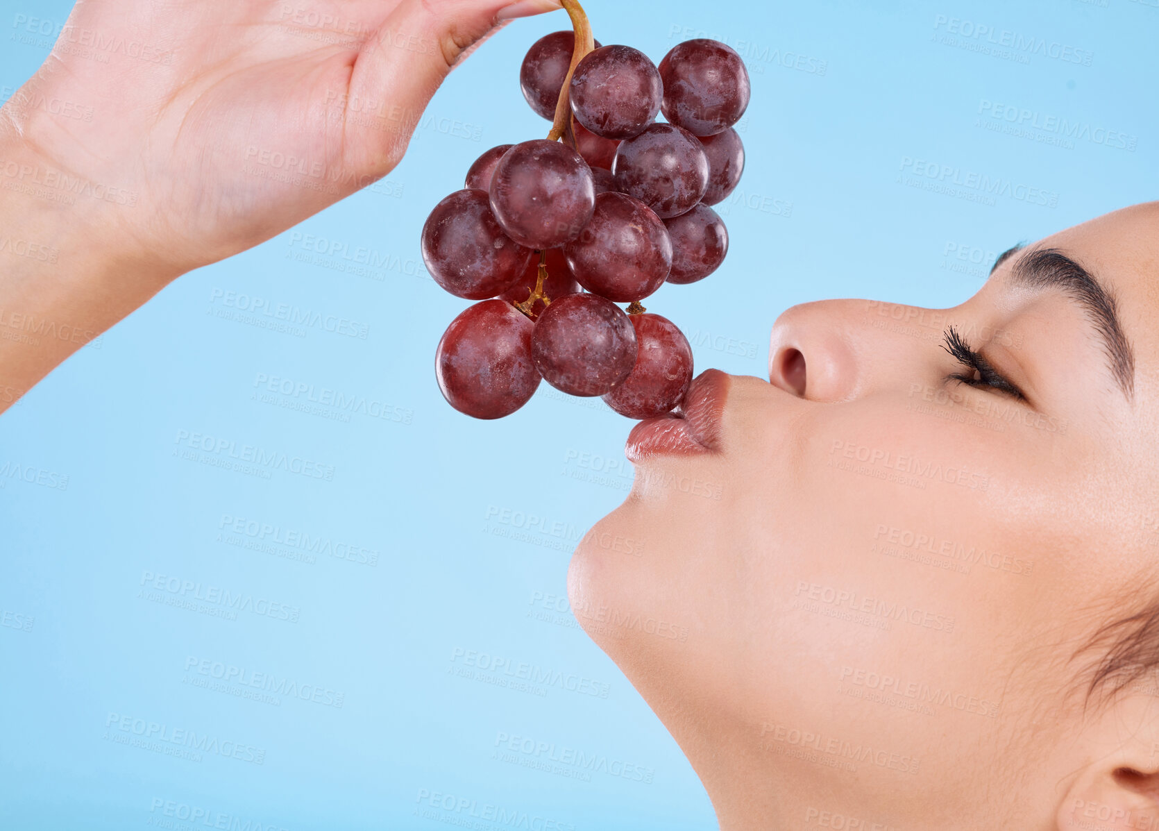 Buy stock photo Girl, face and grapes in studio for beauty with healthy diet, skincare and antioxidant for glowing skin. Model, mockup and kiss a vitamin c fruit for natural cosmetics and wellness on blue background