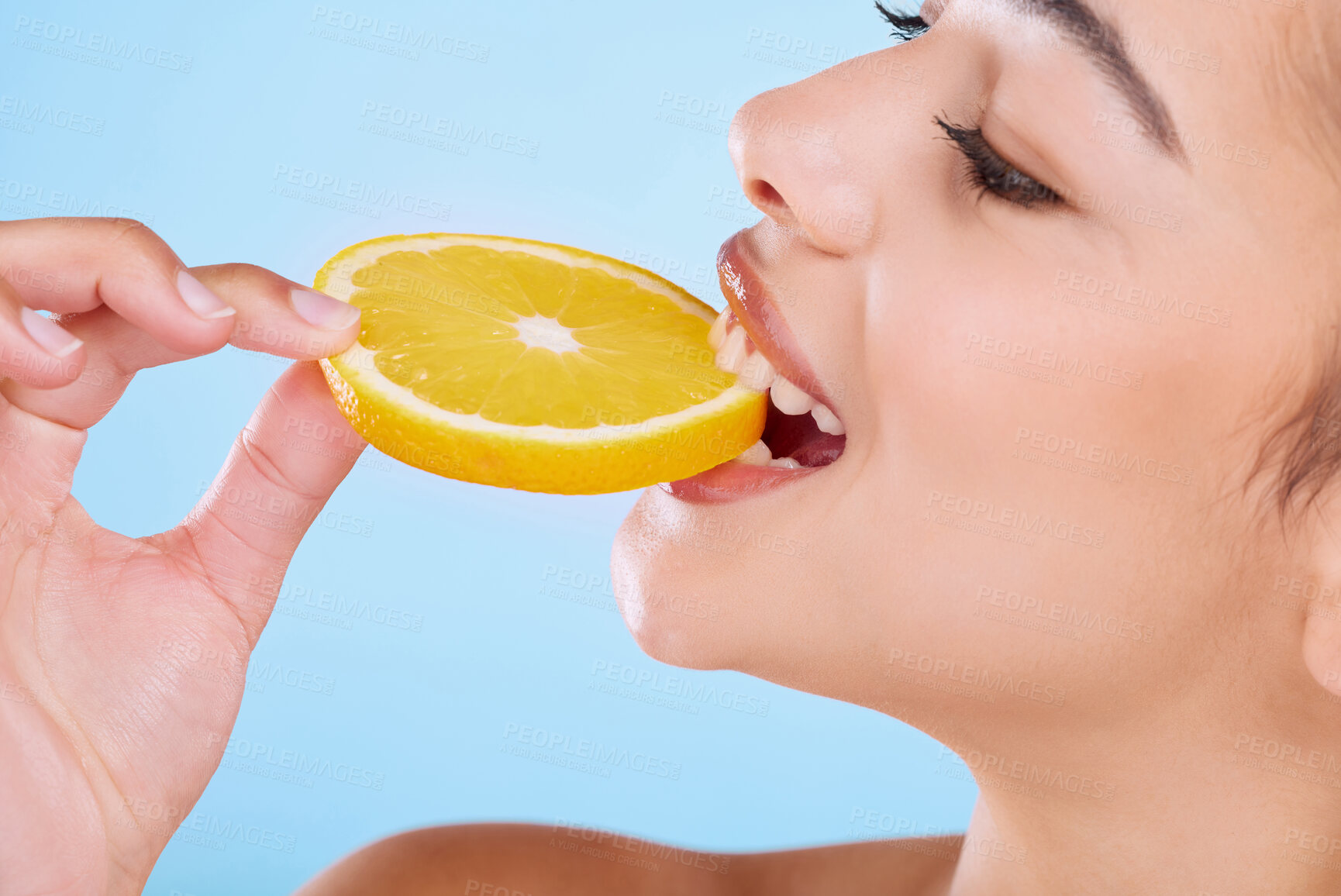 Buy stock photo Girl, eating and orange in studio for skincare with healthy diet, beauty or hydration for glowing skin. Model, bite and happy with vitamin c fruit for natural cosmetics or wellness on blue background