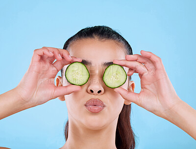 Buy stock photo Studio shot of an attractive young woman posing with two slices of cucumber against a blue background