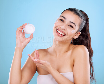 Buy stock photo Studio portrait of an attractive young woman posing with moisturizer to her face against a grey background