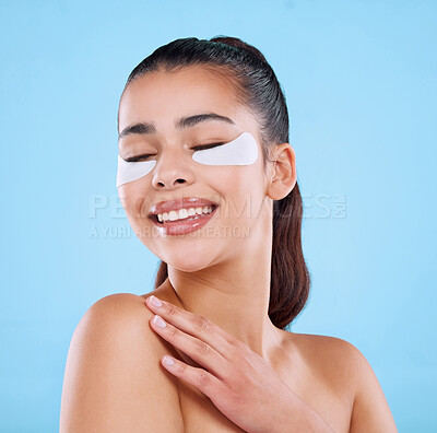 Buy stock photo Studio shot of an attractive young woman wearing under eye patches against a blue background