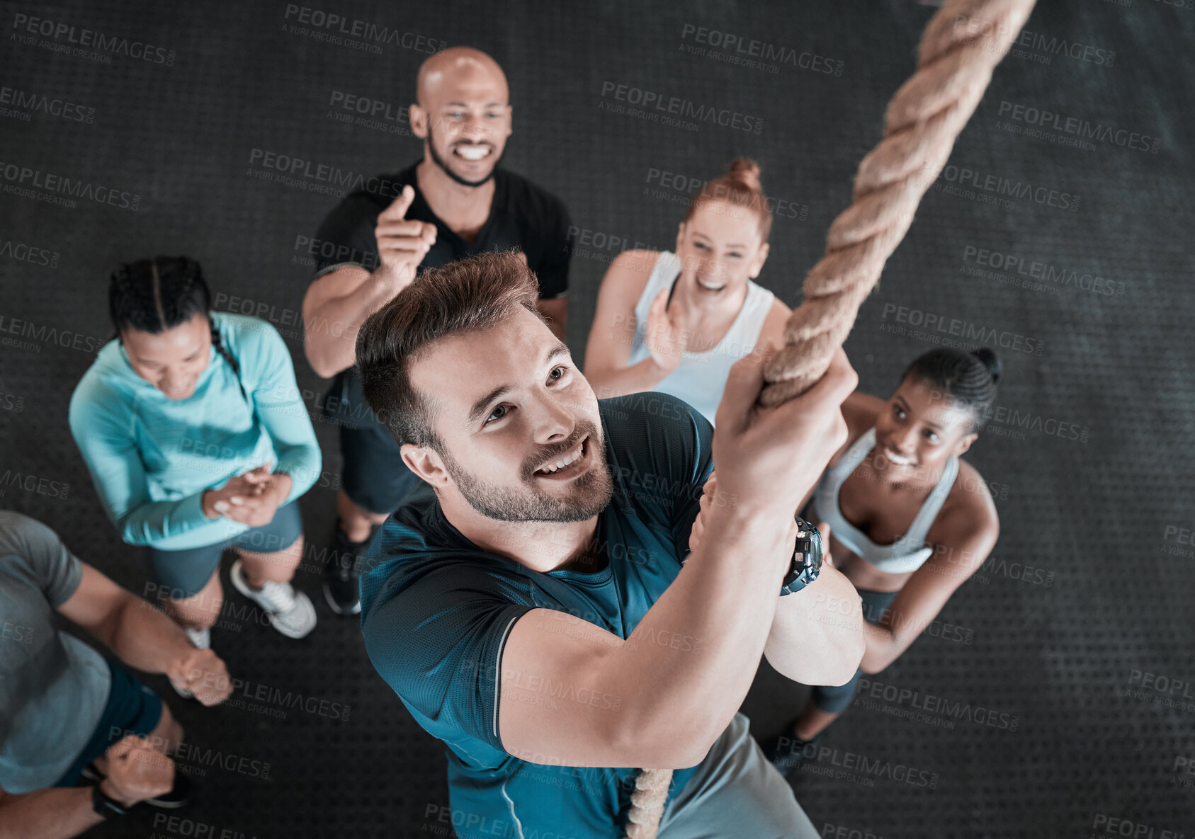 Buy stock photo Shot of a young man climbing a rope while his friends cheer him on