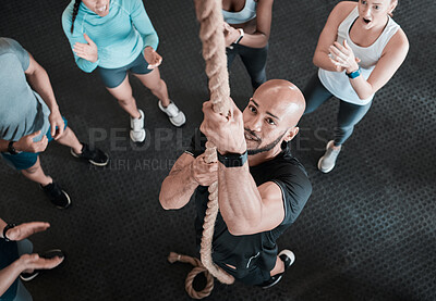 Buy stock photo Shot of a young man climbing a rope while his friends cheer him on