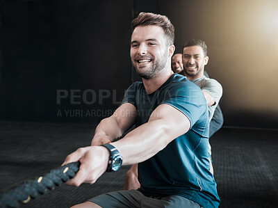 Buy stock photo Shot of a group of gym partners pulling a rope in tug of war together