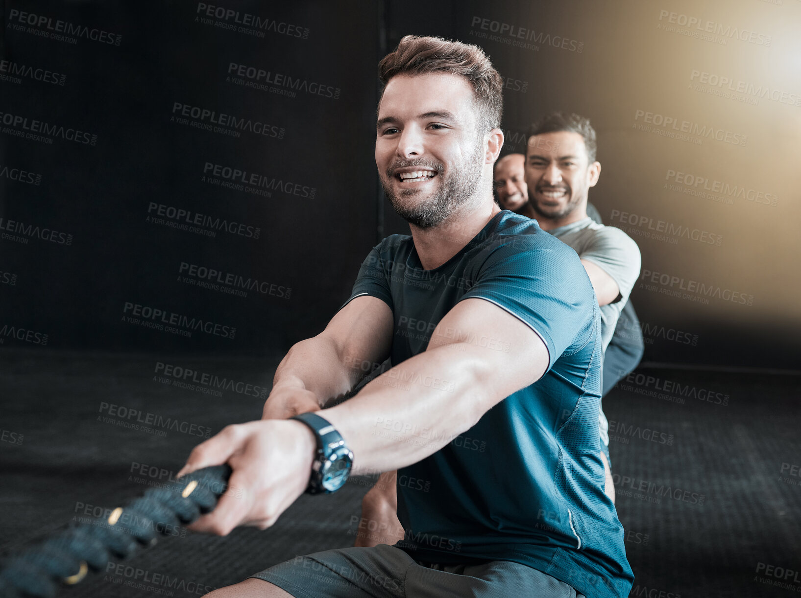 Buy stock photo Shot of a group of gym partners pulling a rope in tug of war together