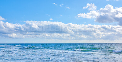 Buy stock photo Beautiful, blue ocean view of the sea with white clouds on a beach day in summer. Outdoors tidal landscape of calm water, sky and waves in nature. Peaceful outdoor coastal setting outside.