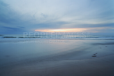 Buy stock photo A beautiful, calm and quiet view of the beach and sunset sky over the horizon with copy space. A peaceful and scenic landscape of endless sandy water of the sea or ocean during low tide at dusk