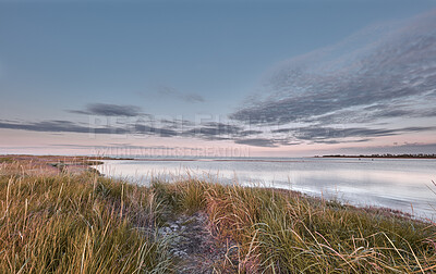 Buy stock photo Beautiful, peaceful and calm view of a lake side with green grass against a cloudy blue sky background. Scenic landscape of a peaceful pond with clean water in the morning