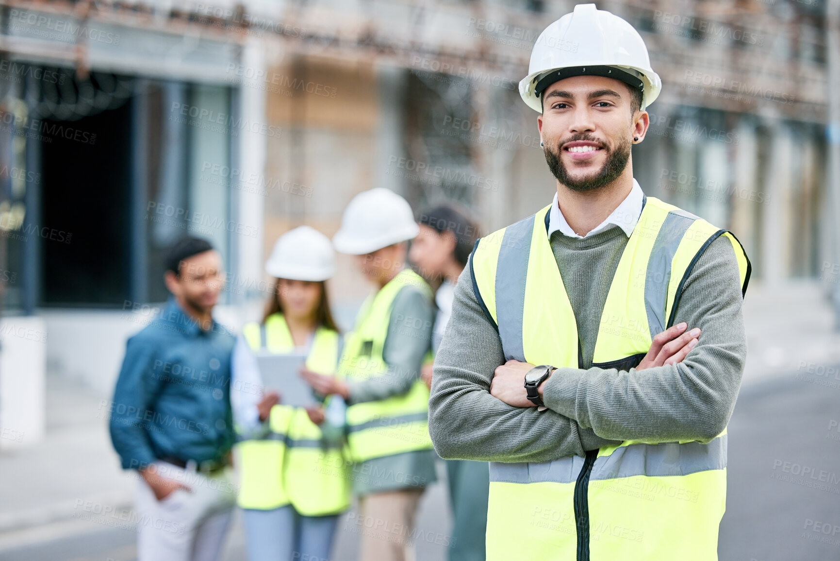 Buy stock photo Shot of a handsome male construction worker standing with his arms folded outside