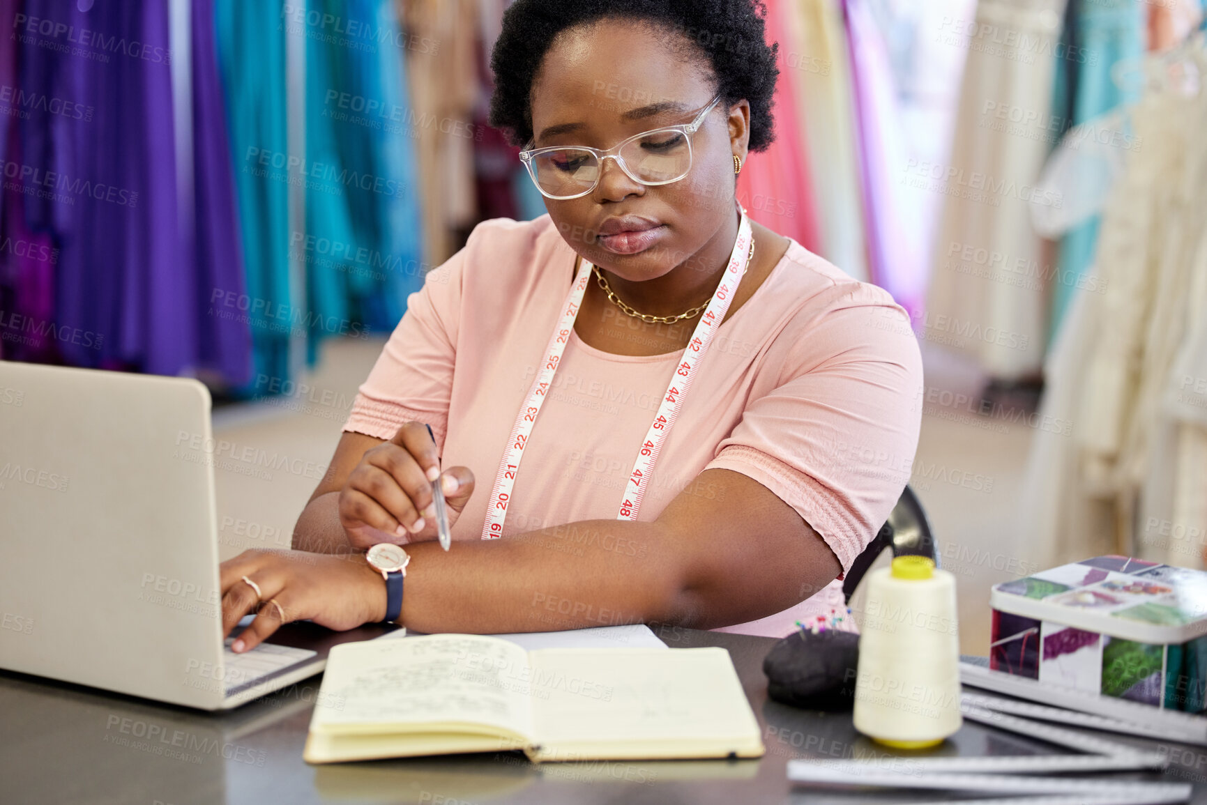 Buy stock photo Woman, fashion designer and book with laptop in workshop for planning, fitting information or writing. Creative, small business and female person with tape measure for ideas, boutique or seamstress