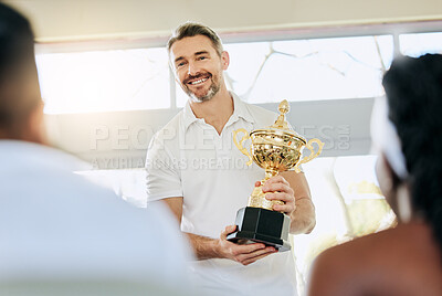 Buy stock photo Cropped shot of a handsome mature tennis coach standing with a trophy in the clubhouse during prizegiving