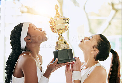 Buy stock photo Cropped shot of two attractive young female tennis players kissing a trophy while standing in the clubhouse during their award ceremony