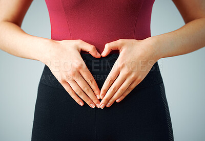 Buy stock photo Heart hands, belly and woman with stomach diet, holistic gut wellness and fitness on gray studio background. Closeup, lose weight and model with gesture, symbol for love and balance with healthy body