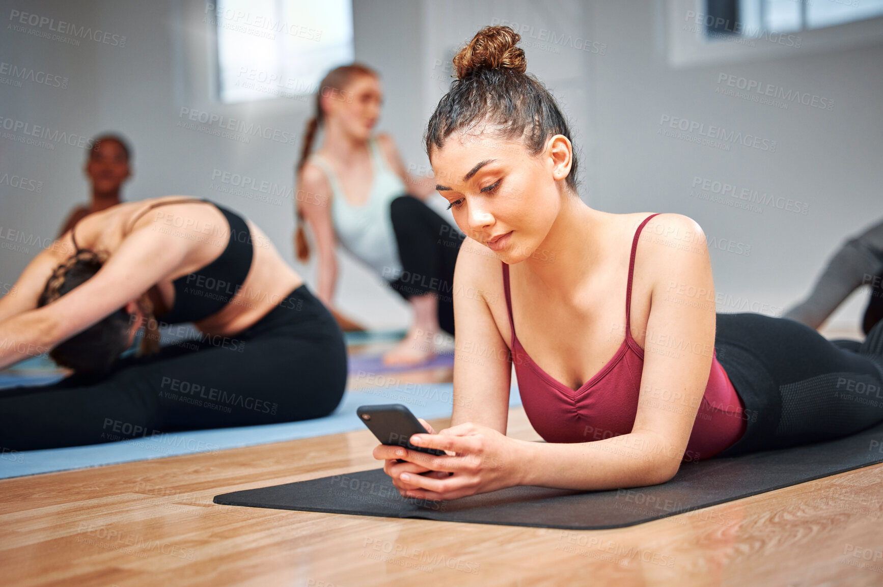 Buy stock photo Shot of a young woman using her smartphone during a yoga lesson