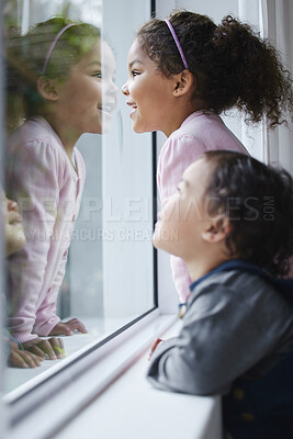 Buy stock photo Girls, sisters and looking by window in home for bonding, curiosity and watching with smile and reflection. Children, siblings and waiting to play by glass in house for fun, relax and joy on weekend 