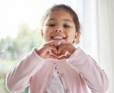 Buy stock photo Girl, child and heart hands in home portrait, love symbol and sign for kindness or peace in lounge. Female person, kid and emoji for support or thank you gesture, vote and shape for care or icon