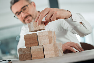 Buy stock photo Businessman, building and wooden blocks on office table for plan, strategy or growth on investment. Happy man, CEO or employee stacking or piling wood for insurance, puzzle or problem solving on desk