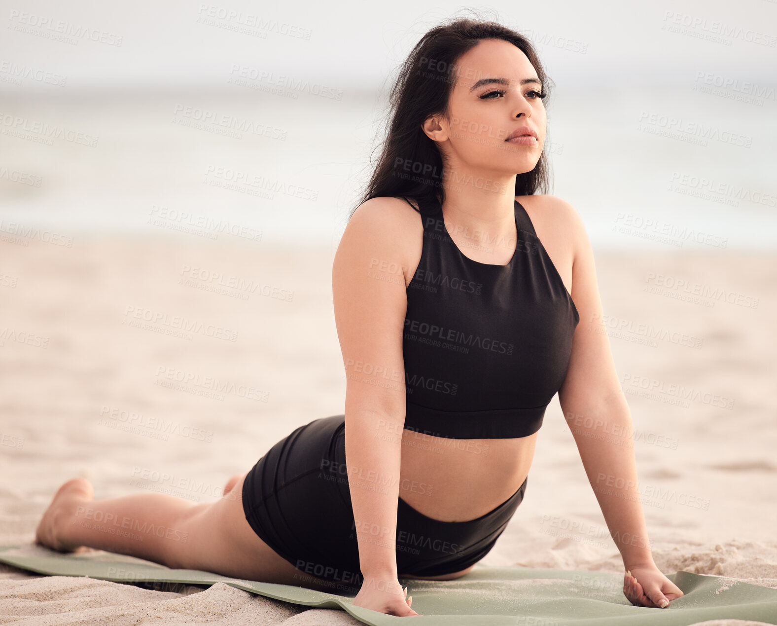 Buy stock photo Shot of an attractive young woman practising yoga at the beach