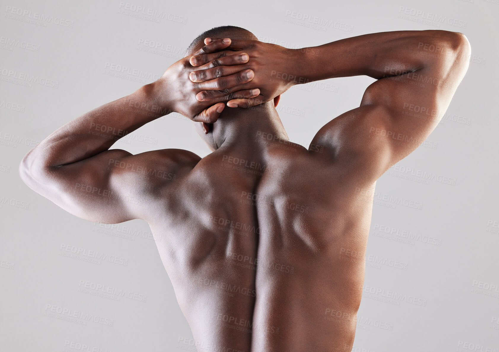 Buy stock photo Rearview shot of a muscular young man posing against a grey background