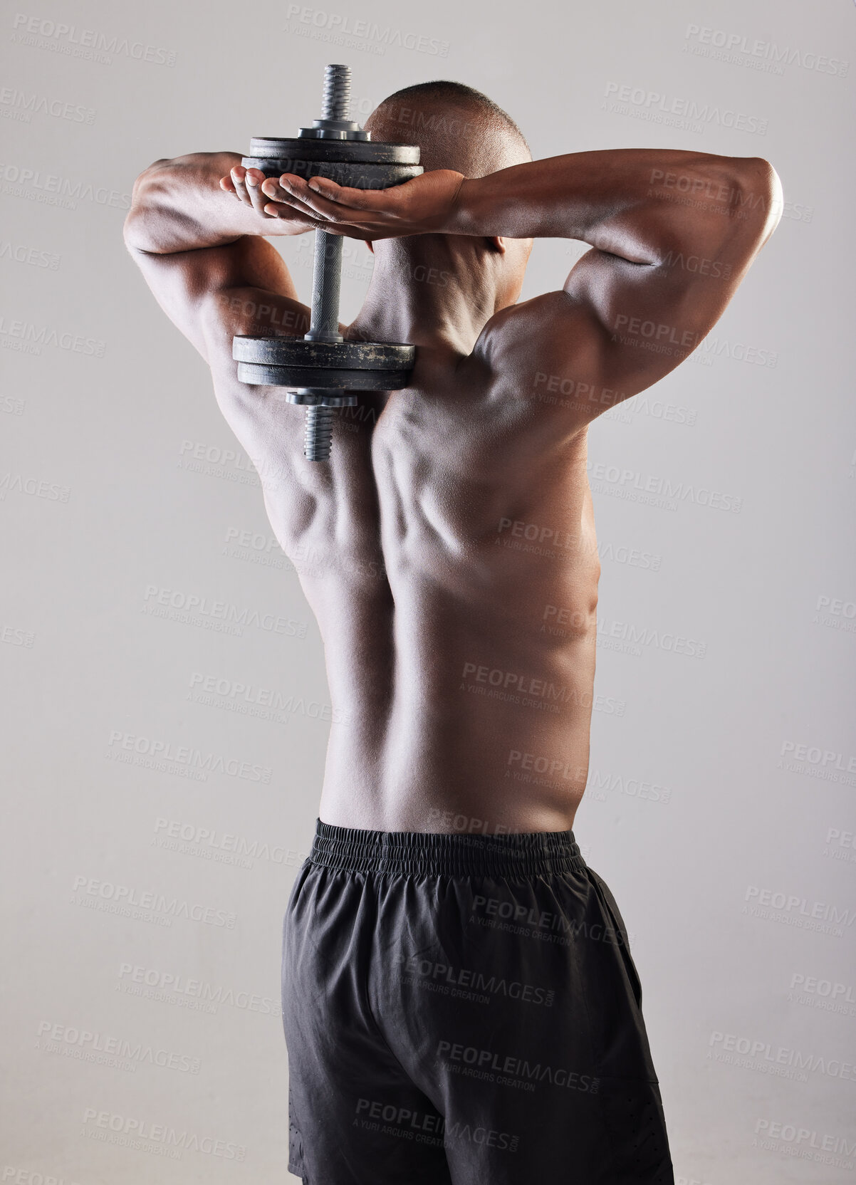 Buy stock photo Rearview shot of a muscular young man posing against a grey background