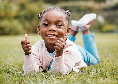 Buy stock photo Shot of a little girl giving the thumbs up while relaxing in her yard