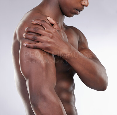Buy stock photo Cropped shot of an unrecognisable man standing alone in the studio and suffering from a shoulder injury