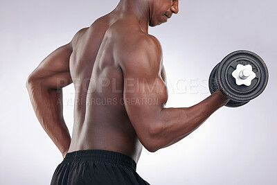 Buy stock photo Cropped shot of an unrecognisable man standing alone in the studio and using a dumbbell to workout