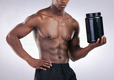 Buy stock photo Cropped shot an unrecognisable man standing alone in the studio and holding a tub of whey protein