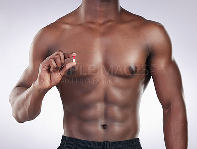 Buy stock photo Cropped shot of an unrecognsiable man standing alone in the studio and holding a supplement pill