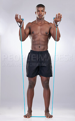 Buy stock photo Full length shot of a handsome young man standing alone in the studio and using resistance bands during his workout