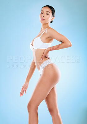 Buy stock photo Studio shot of an attractive woman posing in her underwear against a blue background