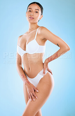 Buy stock photo Studio shot of an attractive woman posing in her underwear against a blue background