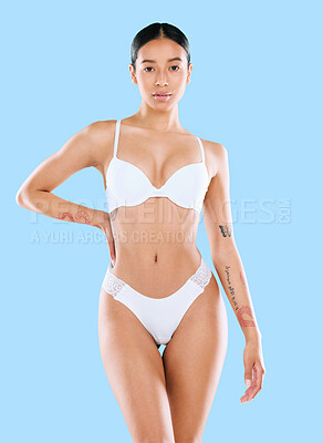 Buy stock photo Studio shot of an attractive woman posing in her underwear against a blue background