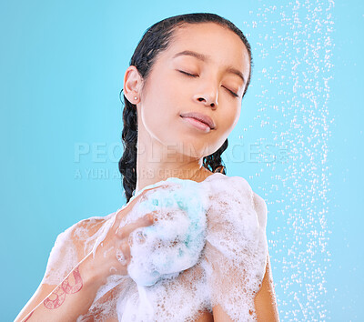 Buy stock photo Studio shot of an attractive young woman showering against a blue background