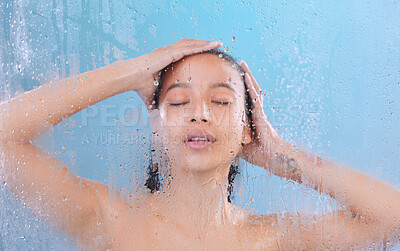 Buy stock photo Studio shot of an attractive young woman showering against a blue background