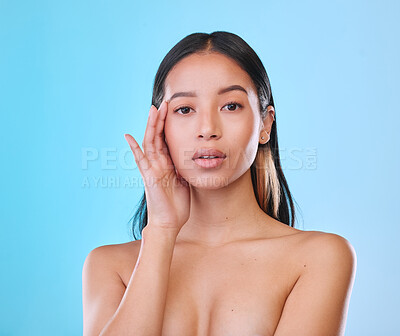 Buy stock photo Studio portrait of an attractive young woman posing against a blue background