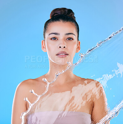 Buy stock photo Shot of a beautiful young woman being splashed with water against a blue background