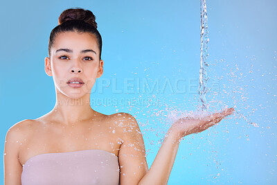 Buy stock photo Water splash, portrait and woman in studio for shower, hygiene or wellness isolated on blue background. Confidence, washing and face of model cleaning for skincare, beauty and bath for dermatology