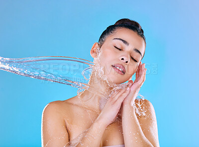 Buy stock photo Shot of a beautiful young woman being splashed with water against a blue background